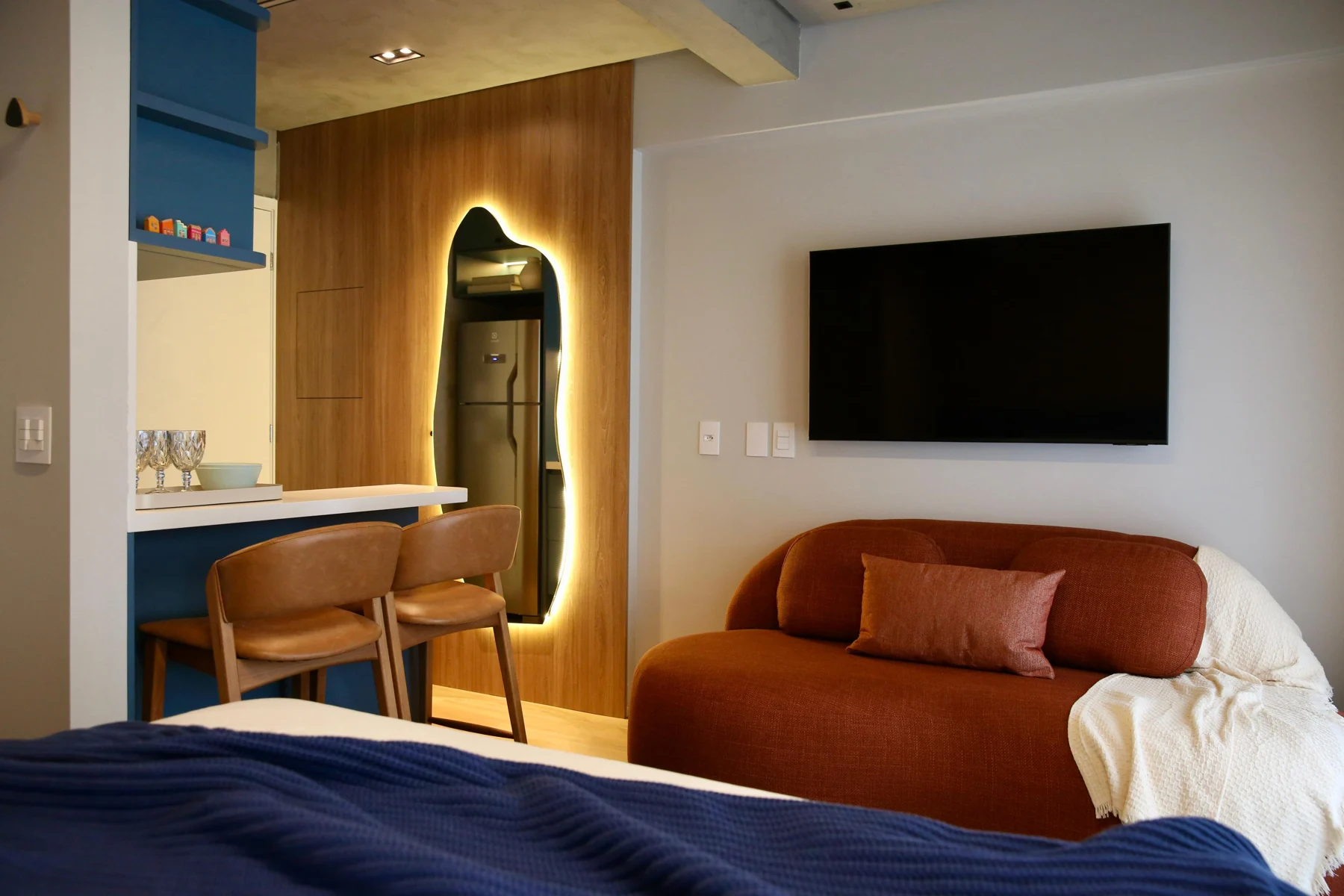 Ambiente integrado com sofá, cama e marcenaria